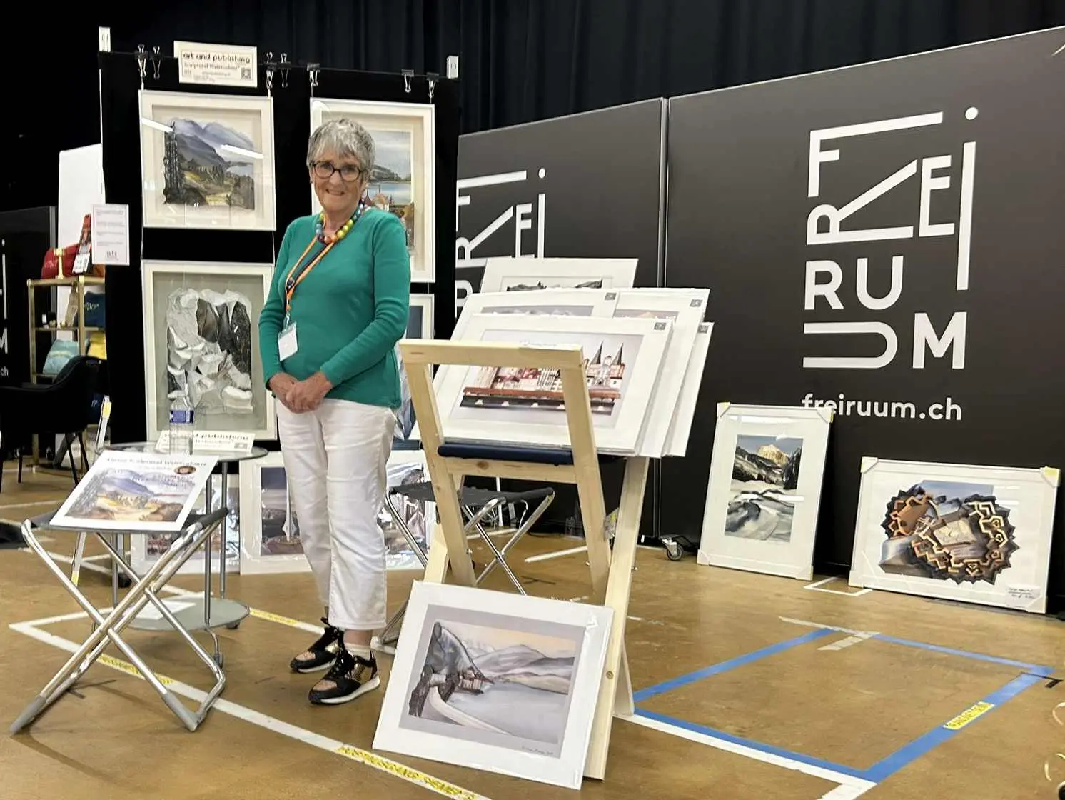 Sculptural Watercolour® paintings on a display panel at Expat Expo Zug, including alpine and architectural themes