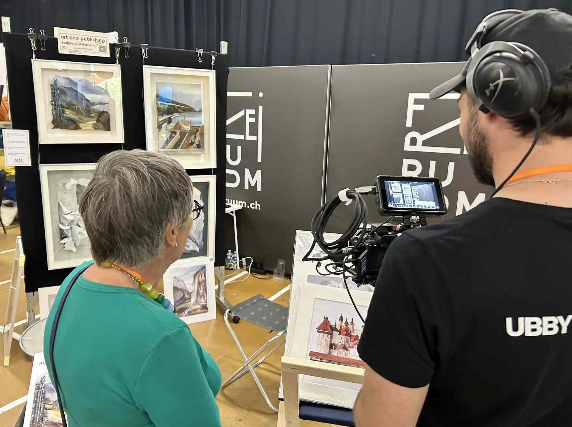 Prue Bishop discussing her technique at the Expat Expo Zug, artworks and prints in background
